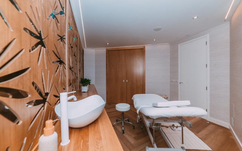 Sala de spa con lavabo blanco y pared de madera, parte del Proyecto Wellness Parque Santiago 3.